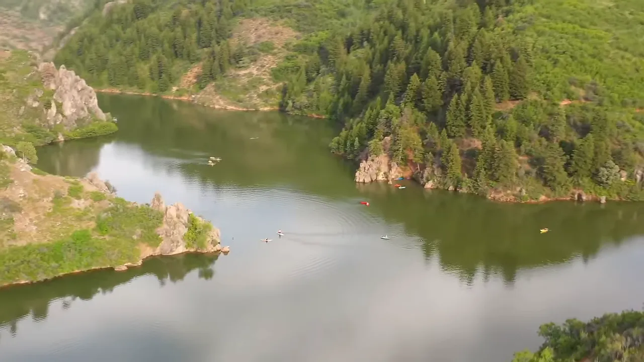 Bright blue reservoir with surrounding cliffs and people enjoying summer water activities