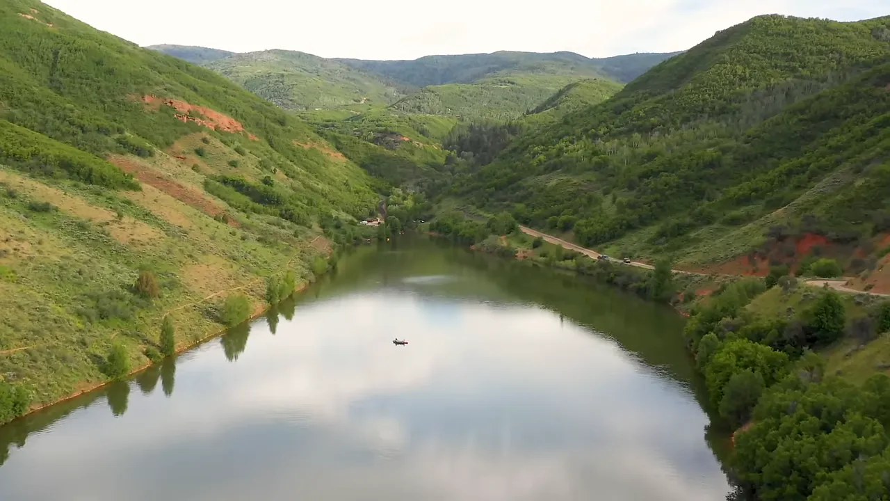 A calm alpine-style reservoir with tree-lined shore and clear water